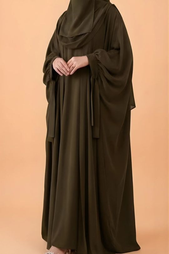 Brown abaya worn by a person on a beige background