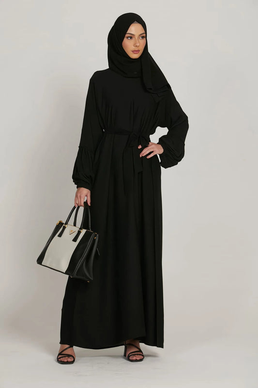 Side profile of black abaya dress highlighting flowy silhouette and elasticated cuffs