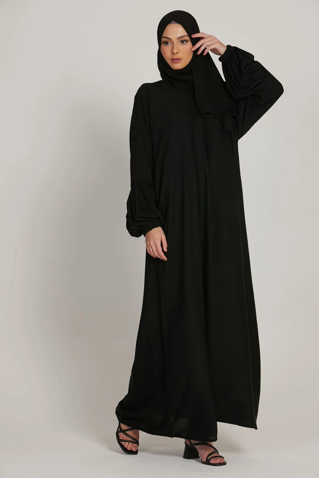 Woman wearing black abaya dress with simple elasticated cuffs, styled modestly for everyday wear