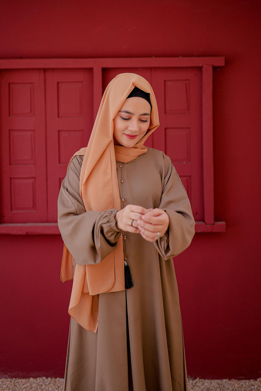 Zoomed-in shot of elastic cuff design on plain light brown abaya