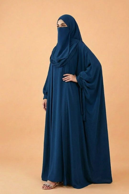 Person wearing a blue abaya on an orange background