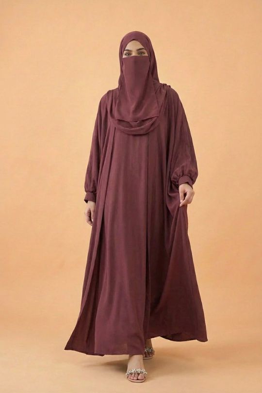 Woman wearing a long burgundy dress and hijab on a beige background