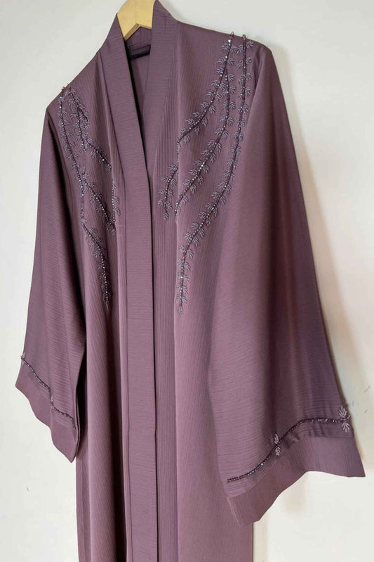 Soft pink Essence of Dreams abaya hanging on hanger showing premium nida fabric and refined front open design