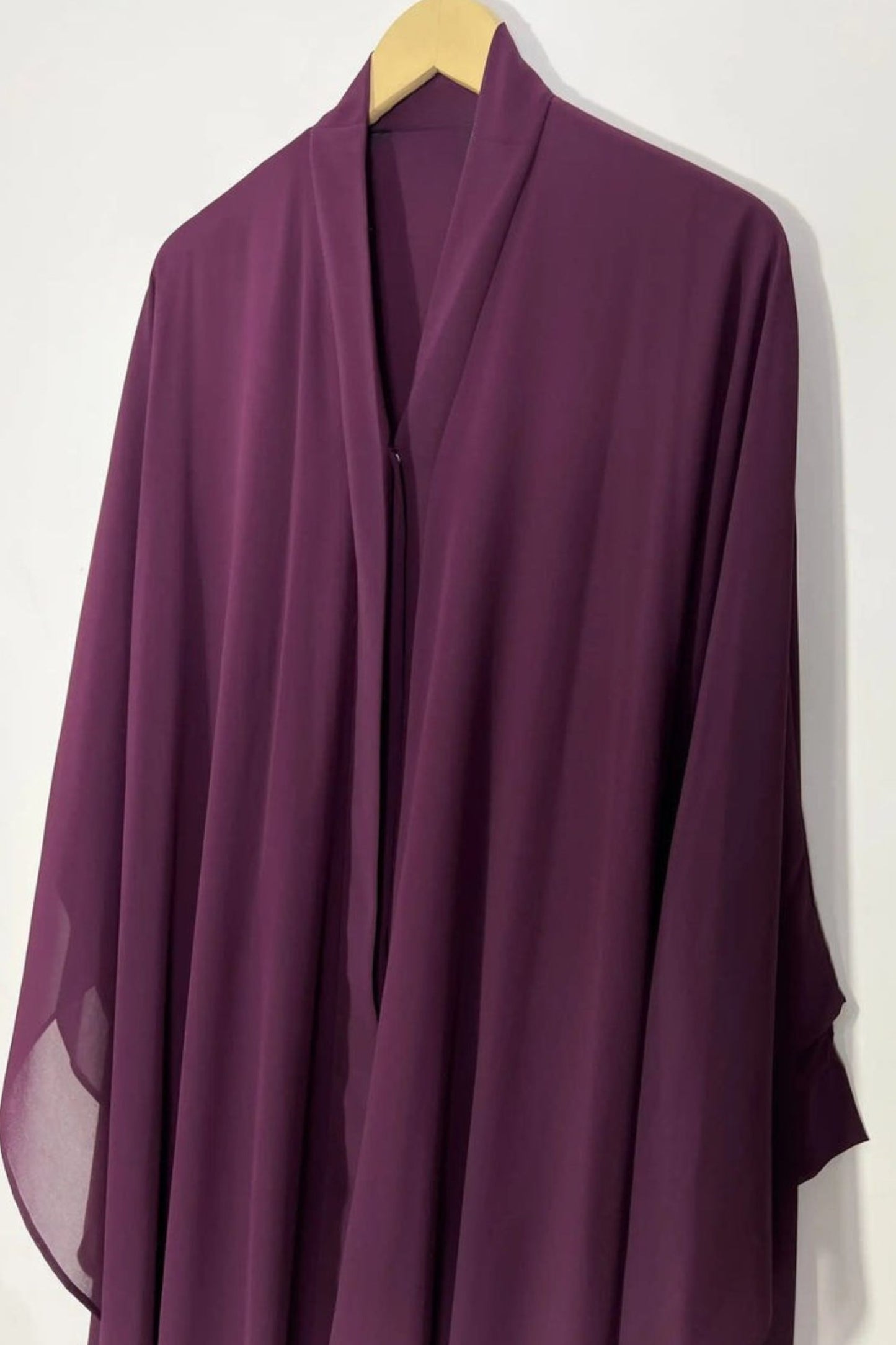Front view of maroon Halimah butterfly abaya on hanger highlighting lightweight chiffon and refined drape
