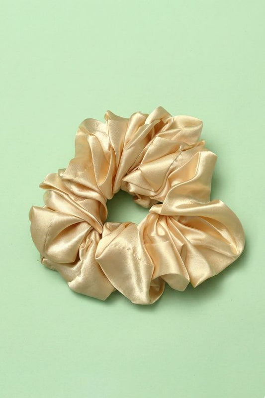 Gold satin scrunchie on a light green background