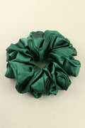 Green satin scrunchie on a beige background
