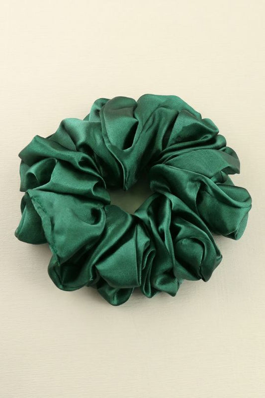 Green satin scrunchie on a beige background