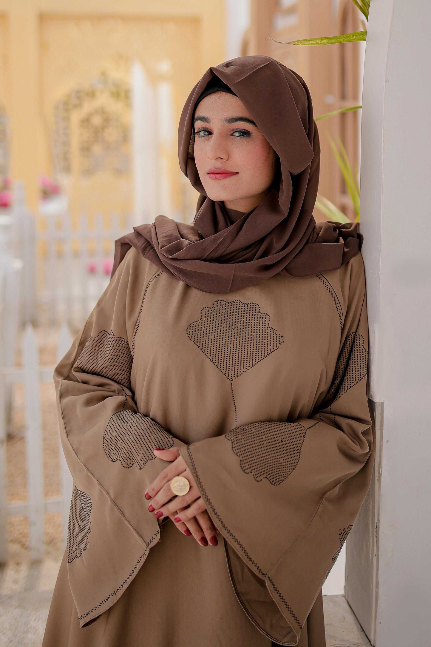 Zoomed-in view of fabric and flower nug detailing on light brown abaya
