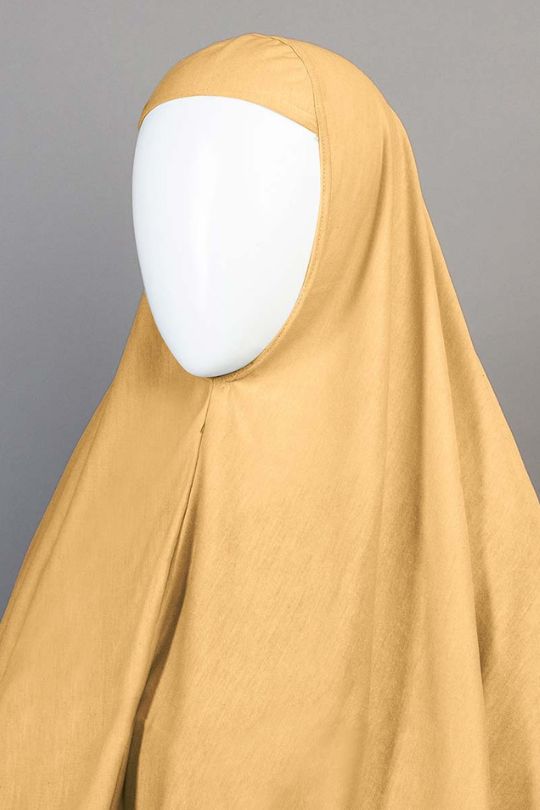 Mustard-colored hijab on a mannequin head against a gray background