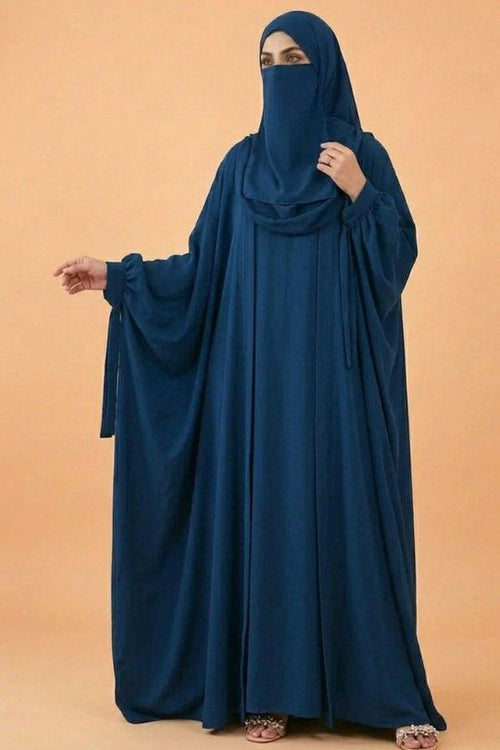 Person wearing a blue abaya against an orange background