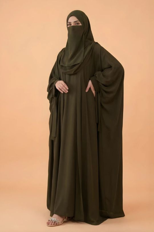 Person wearing a long dark green abaya on a beige background