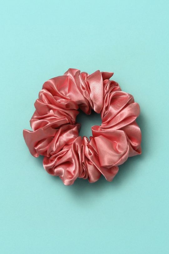 Pink satin scrunchie on a light blue background