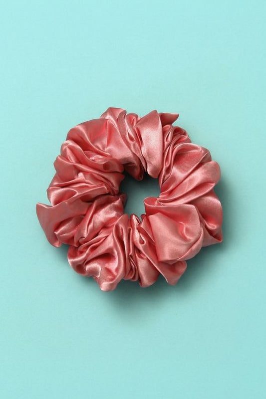 Pink satin scrunchie on a light blue background