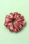 Pink satin scrunchie on a light green background