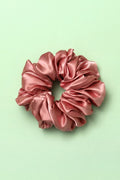 Pink satin scrunchie on a light green background