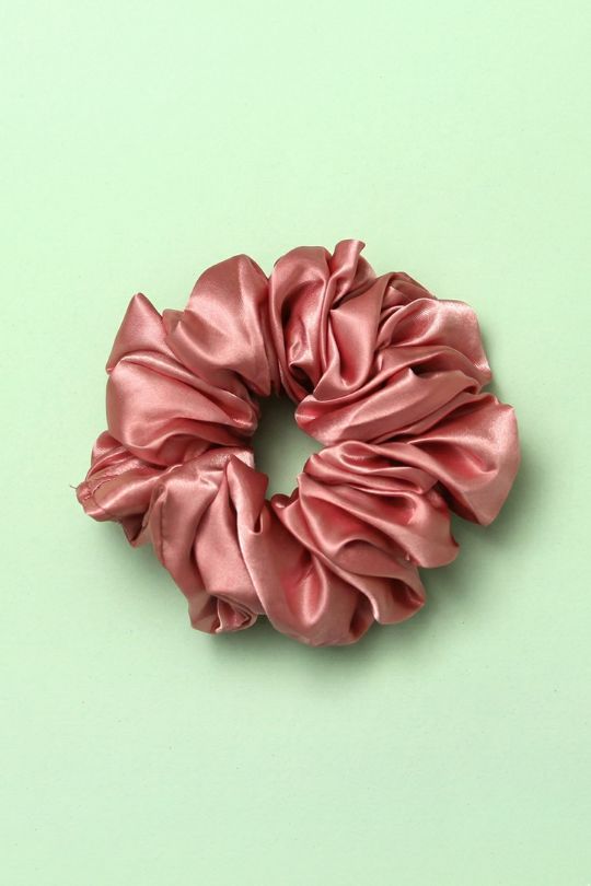 Pink satin scrunchie on a light green background