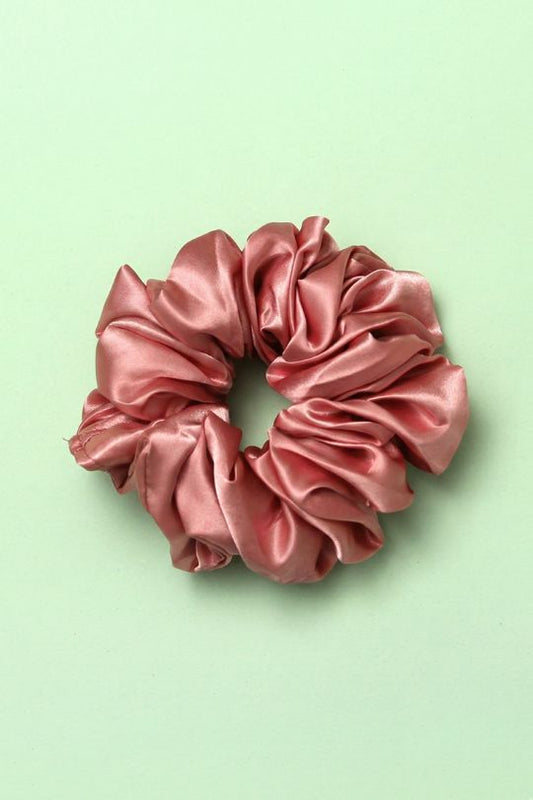 Pink satin scrunchie on a light green background