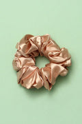 Pink satin scrunchie on a light green background