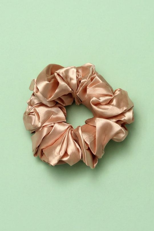 Pink satin scrunchie on a light green background