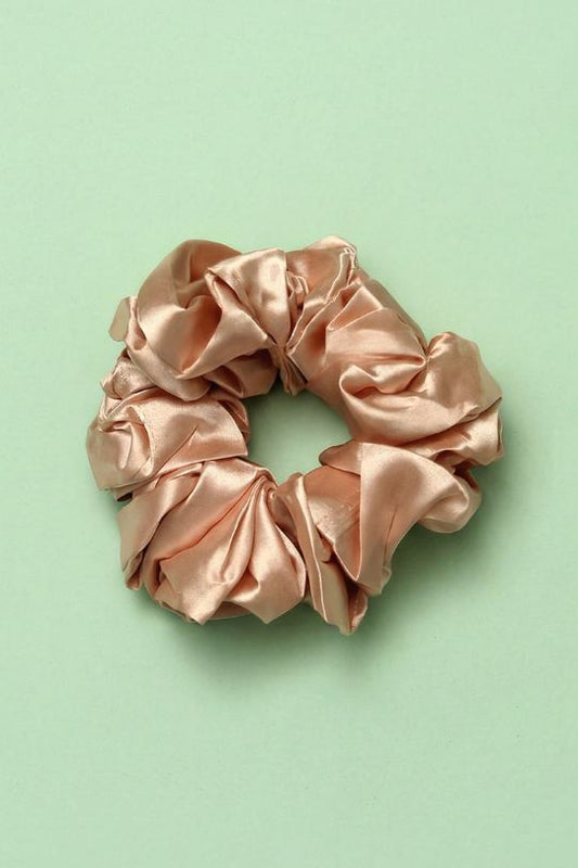 Pink satin scrunchie on a light green background