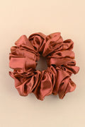 Reddish-brown satin scrunchie on a beige background