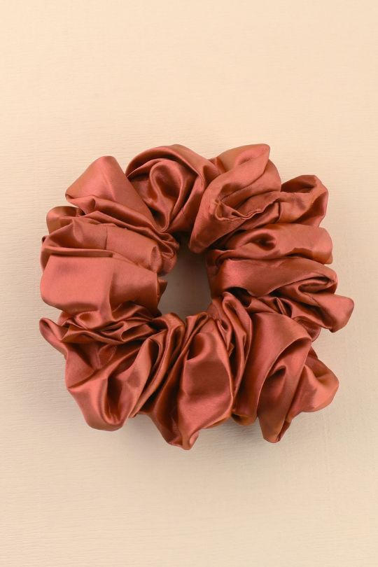 Reddish-brown satin scrunchie on a beige background