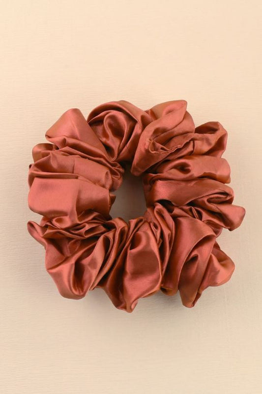 Reddish-brown satin scrunchie on a beige background