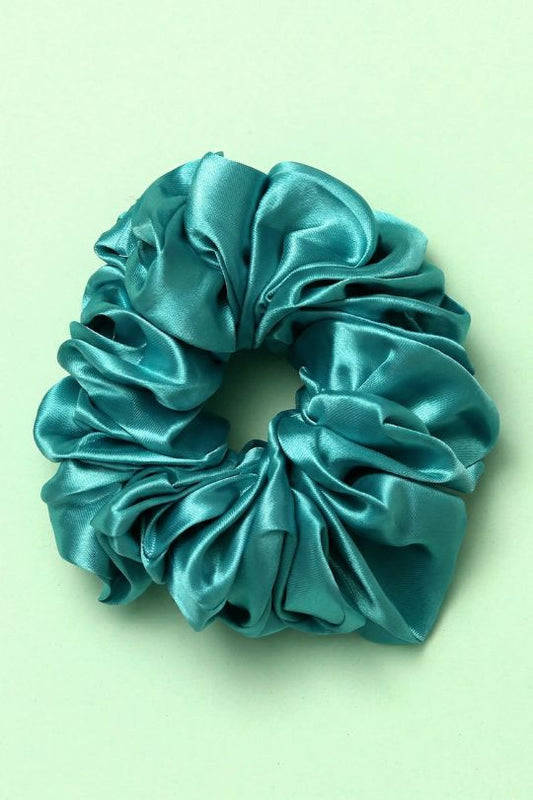 Turquoise satin scrunchie on a light green background