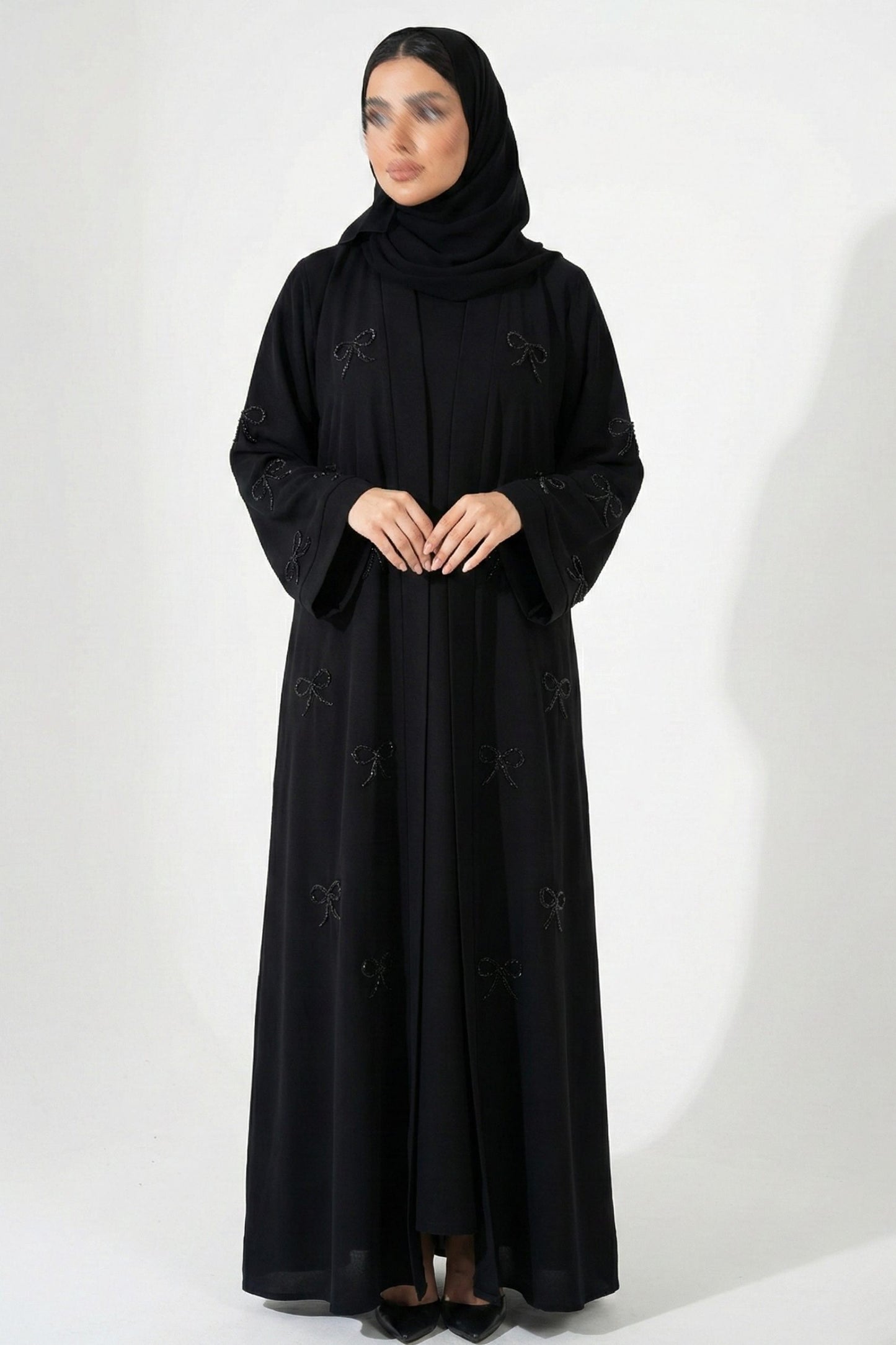 Front full view of black handworked abaya highlighting front open design and delicate handwork bows on sleeves