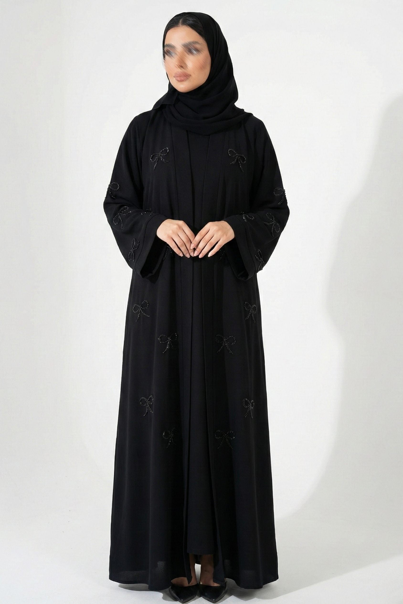 Front full view of black handworked abaya highlighting front open design and delicate handwork bows on sleeves