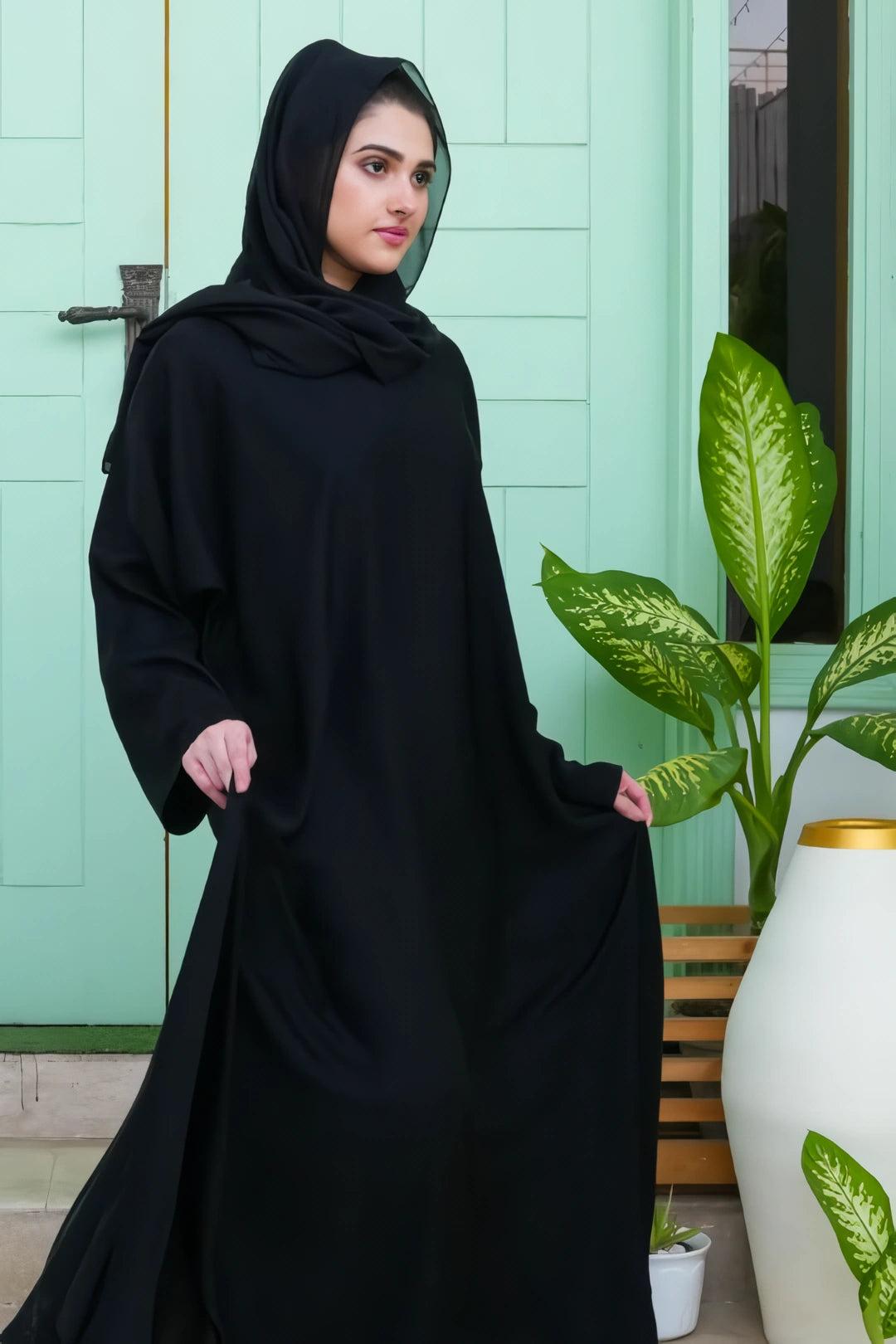 Side full view showing the elegant drape and modest fit of the Plain Black Abaya made from soft Nida fabric.