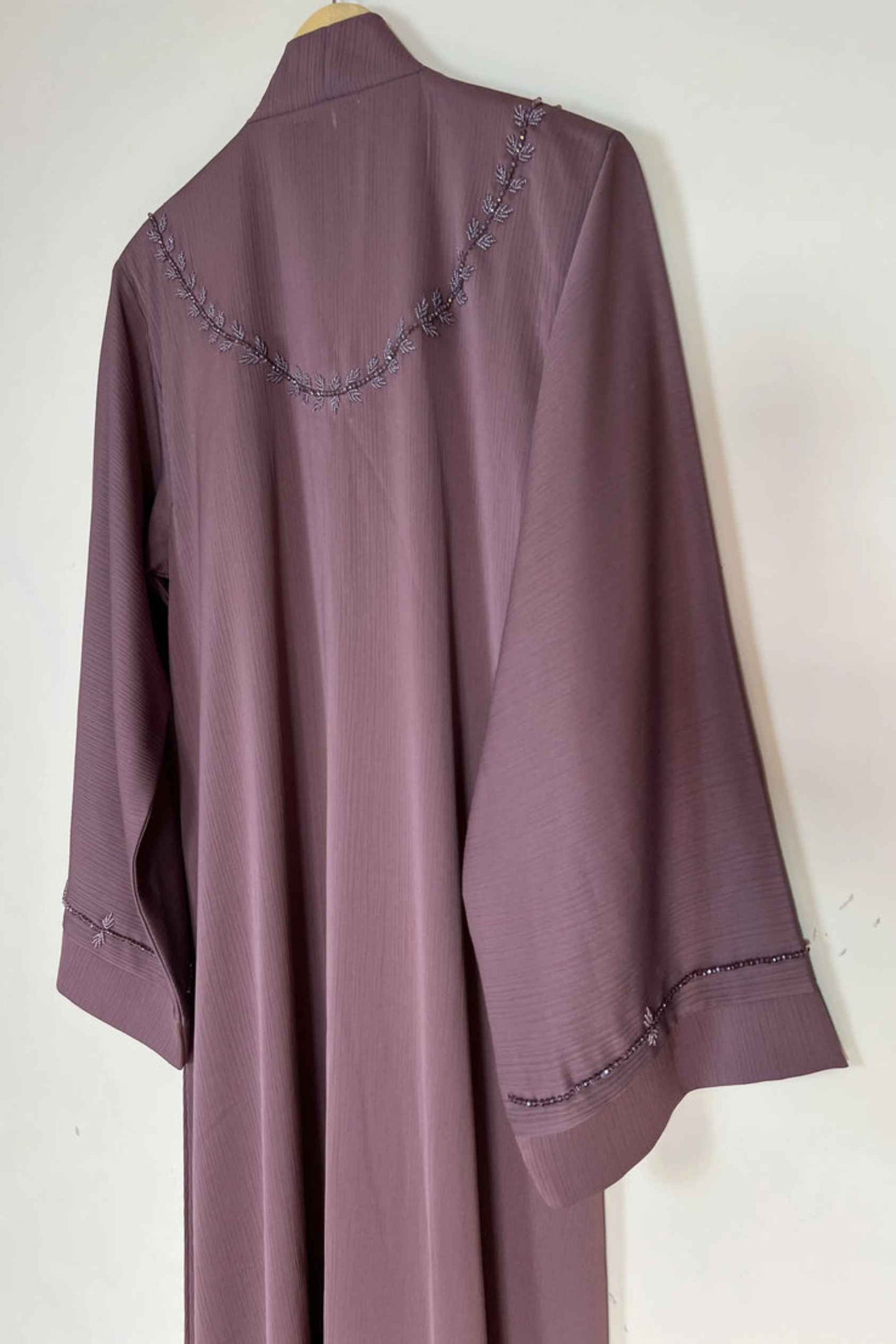 Back side full view of soft pink premium nida abaya hanging on hanger showing smooth fall and modest elegant finish
